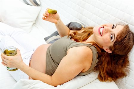 simsearch:400-05911635,k - Smiling beautiful pregnant woman relaxing on sofa at home and  holding  jar of pickles in hands Foto de stock - Super Valor sin royalties y Suscripción, Código: 400-04234839