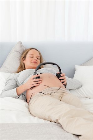 simsearch:400-04266869,k - Cute future mom putting headphones on her belly lying on a bed Stock Photo - Budget Royalty-Free & Subscription, Code: 400-04235215
