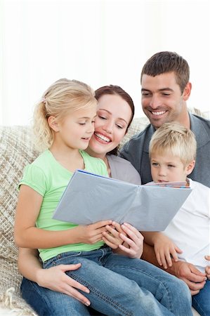 family photos in album - Adorable family reading a book together in the living-room at home Stock Photo - Budget Royalty-Free & Subscription, Code: 400-04235244