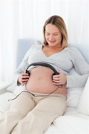 simsearch:400-04767824,k - Adorable future mom putting headphones on her belly lying on a bed Foto de stock - Royalty-Free Super Valor e Assinatura, Número: 400-04235243