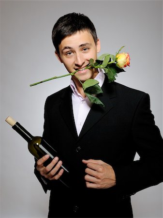 simsearch:400-04655735,k - Handsome romantic young man holding rose flower and vine bottle  prepared for a date. gray background Stockbilder - Microstock & Abonnement, Bildnummer: 400-04235644