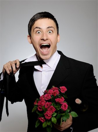 simsearch:400-04655735,k - Happy romantic husband holding rose flower and vine bottle and unknotting his tie. gray background Stockbilder - Microstock & Abonnement, Bildnummer: 400-04235645