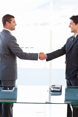 simsearch:400-04769433,k - Cheerful businessmen closing a deal by shaking their hands at the office Foto de stock - Royalty-Free Super Valor e Assinatura, Número: 400-04235841