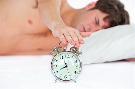 simsearch:400-04287303,k - Asleep young man stopping his ringing alarm clock in the bedroom at home Stockbilder - Microstock & Abonnement, Bildnummer: 400-04235873