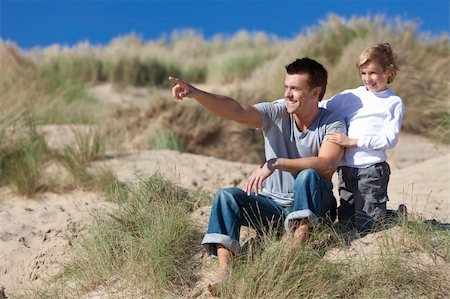 simsearch:400-04235471,k - A man and young boy, father and son, sitting down and having fun in the sand dunes of a sunny beach, the father is pointing into the distance. Stock Photo - Budget Royalty-Free & Subscription, Code: 400-04236902