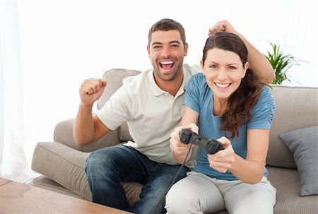 simsearch:625-02931506,k - Cheerful man encouraging his girlfriend playing video game at home Stock Photo - Budget Royalty-Free & Subscription, Code: 400-04237354