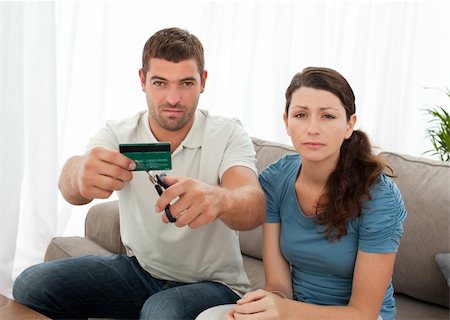 simsearch:400-05746763,k - Worried couple cutting their credit card together sitting on the sofa at home Stock Photo - Budget Royalty-Free & Subscription, Code: 400-04237361