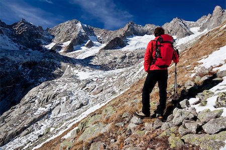 simsearch:400-04359682,k - Back view of a young male hiker while observing a high mountain panorama. Standing position, red jacket, black pant. Triolet glacier, Mount Blanc massif, Italy, Europe. Stock Photo - Budget Royalty-Free & Subscription, Code: 400-04237895