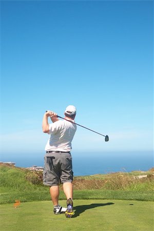 simsearch:400-03997921,k - Young male golfer hitting the ball from the tee box next to the ocean on a beautiful summer day Stock Photo - Budget Royalty-Free & Subscription, Code: 400-04230759