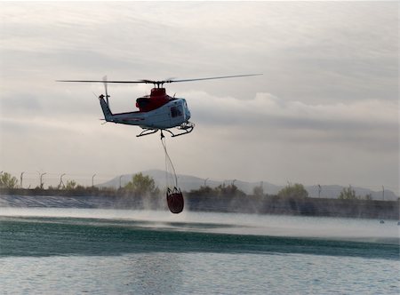 firefighters spray water - Fire brigade helicopter refilling water while extinguising forest fire Photographie de stock - Aubaine LD & Abonnement, Code: 400-04230768