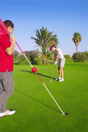 golf woman player putting golf ball and man holds flag Stock Photo - Budget Royalty-Free & Subscription, Code: 400-04231382