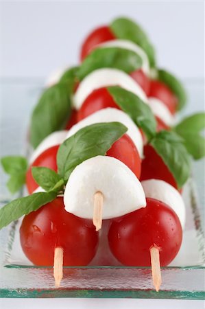 Cherry tomatoes and mozzarella on skewers, garnished with basil leaves and olive oil Stock Photo - Budget Royalty-Free & Subscription, Code: 400-04232384
