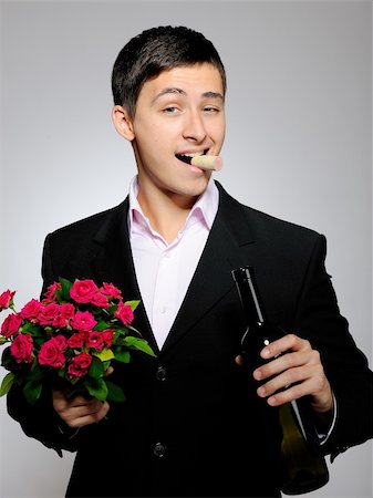 simsearch:400-04655736,k - Handsome romantic young man holding rose flower and vine bottle  prepared for a date. gray background Stockbilder - Microstock & Abonnement, Bildnummer: 400-04232508