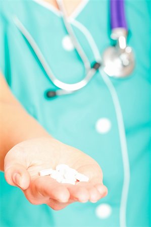 simsearch:400-04018969,k - doctor in the green uniform holding the pills. focus is on the pile of tablets. shallow depth of view. Foto de stock - Royalty-Free Super Valor e Assinatura, Número: 400-04233114