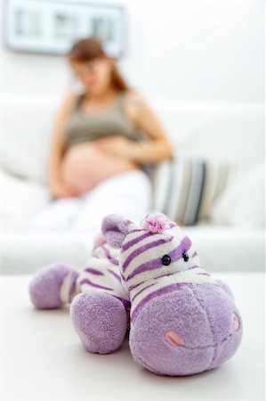 simsearch:400-04688796,k - Toy lying on table and pregnant woman sitting on sofa at home  in background Fotografie stock - Microstock e Abbonamento, Codice: 400-04233450