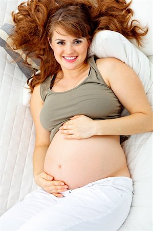 simsearch:400-05911635,k - Happy beautiful pregnant woman relaxing on sofa at home and  holding her belly. Foto de stock - Super Valor sin royalties y Suscripción, Código: 400-04233451