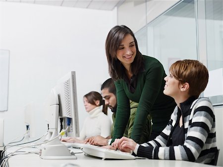 Computer lab with caucasian female teacher helping student. Horizontal shape, side view, waist up, copy space Stock Photo - Budget Royalty-Free & Subscription, Code: 400-04241078