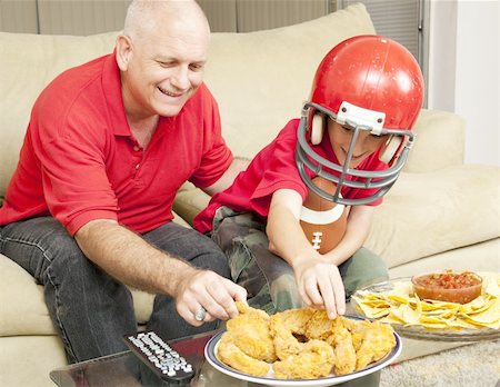 father watching kid in sports - Father and son watching football together and eating snacks. Stock Photo - Budget Royalty-Free & Subscription, Code: 400-04242777