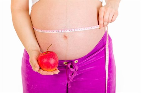 simsearch:400-07892390,k - Pregnant woman measuring her belly and holding apple isolated on white. Close-up. Photographie de stock - Aubaine LD & Abonnement, Code: 400-04243266