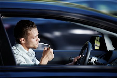 A young man lit a cigarette in a car at speed Stock Photo - Budget Royalty-Free & Subscription, Code: 400-04243421