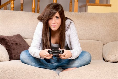 simsearch:400-05059261,k - Young female concentrating playing videogames on sofa at home Stock Photo - Budget Royalty-Free & Subscription, Code: 400-04255376