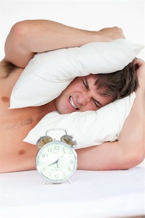 simsearch:400-04287303,k - Man woken up by his alarm clock and putting pillow on his head Stockbilder - Microstock & Abonnement, Bildnummer: 400-04256486