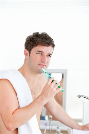 thoughtful man brushing his tooth with towel on his shoulder in the bathroom Stock Photo - Budget Royalty-Free & Subscription, Code: 400-04256483