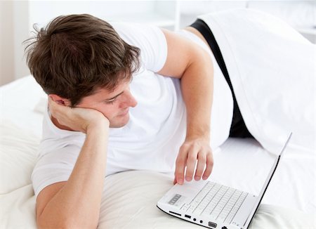 simsearch:400-05209351,k - Cute man using a laptop lying on his bed at home Stock Photo - Budget Royalty-Free & Subscription, Code: 400-04256490