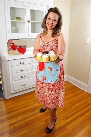 An attractive woman in vintage clothing offers cupcakes to her guests. Stock Photo - Budget Royalty-Free & Subscription, Code: 400-04256679