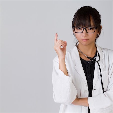 Confident Chinese medical doctor holding finger with serious expression, closeup portrait with copyspace on gray. Stock Photo - Budget Royalty-Free & Subscription, Code: 400-04256912