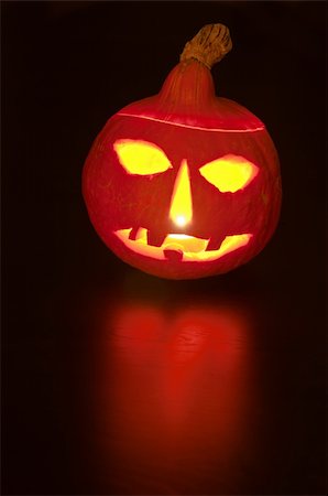 franky242 (artist) - Scary Halloween Pumpkin lit by candle with reflection on dark wooden table Fotografie stock - Microstock e Abbonamento, Codice: 400-04257849