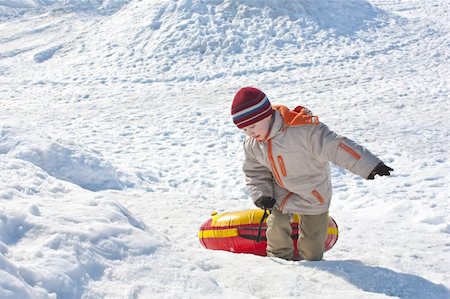Boy drags red-yellow tube on a snow Foto de stock - Super Valor sin royalties y Suscripción, Código: 400-04258829