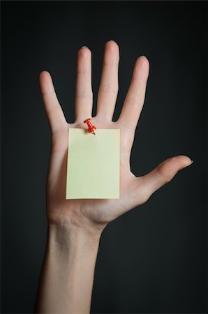 female hand with sticky office note nailed to hand with red pin. Note is blank and yellow. Dark background Stock Photo - Budget Royalty-Free & Subscription, Code: 400-04259252