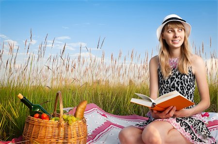 beautiful young woman having picnic on meadow, reading book and smiling. Looking away from camera, blue cloudy sky in background Stock Photo - Budget Royalty-Free & Subscription, Code: 400-04259283