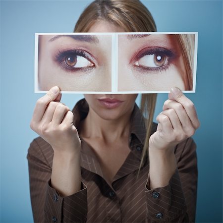 mid adult business woman holding photo of her eyes looking at different sides on blue background. Square shape, front view, waist up Stock Photo - Budget Royalty-Free & Subscription, Code: 400-04266069
