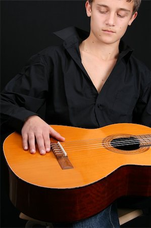 Teenage male in casual attire holding a guitar. FOCUS ON GUITAR by HAND Stock Photo - Budget Royalty-Free & Subscription, Code: 400-04266238