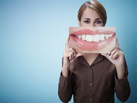 mid adult business woman holding photo of toothy smile on blue background. Horizontal shape, front view, waist up, copy space Stock Photo - Budget Royalty-Free & Subscription, Code: 400-04266337