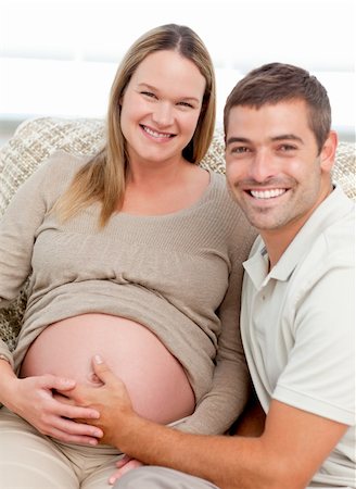 simsearch:400-04266844,k - Portrait of future parents in the living room smiling at the camera Stock Photo - Budget Royalty-Free & Subscription, Code: 400-04266834