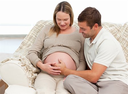 simsearch:400-04266840,k - Cute man feeling his baby putting the hand on his wife's belly in the living room Photographie de stock - Aubaine LD & Abonnement, Code: 400-04266837