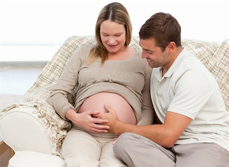 simsearch:400-07322828,k - Cute man feeling his baby putting the hand on his wife's belly in the living room Fotografie stock - Microstock e Abbonamento, Codice: 400-04266837