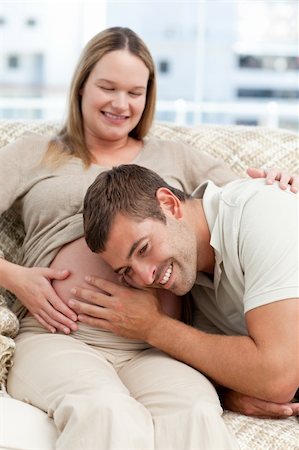 simsearch:400-04266840,k - Attentive man listening to the belly of his wife in the living room Photographie de stock - Aubaine LD & Abonnement, Code: 400-04266838