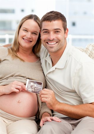 simsearch:400-04266844,k - Proud couple of future parents holding an echography sitting on the sofa Stock Photo - Budget Royalty-Free & Subscription, Code: 400-04266844