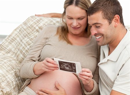 simsearch:400-04266844,k - Lovely couple looking at an echography while relaxing in the living-room Stock Photo - Budget Royalty-Free & Subscription, Code: 400-04266848