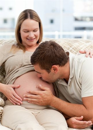 simsearch:400-04266840,k - Attentive man kissing his wife's belly while relaxing on the sofa at home Photographie de stock - Aubaine LD & Abonnement, Code: 400-04266841