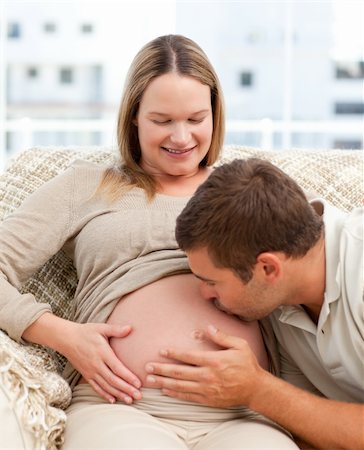 simsearch:400-04266840,k - Proud man kissing the belly of his pregnant girlfriend sitting in the sofa in the living room Photographie de stock - Aubaine LD & Abonnement, Code: 400-04266842