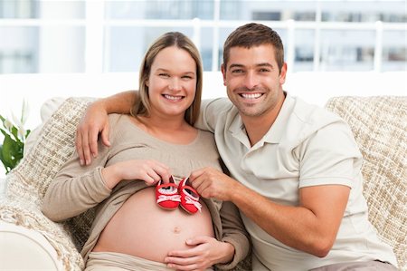 simsearch:400-04266844,k - Future parents playing with baby shoes sitting on the sofa at home Stock Photo - Budget Royalty-Free & Subscription, Code: 400-04266855