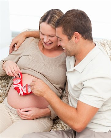 simsearch:400-04266840,k - Cute man playing with baby shoes on his wife's belly at home Photographie de stock - Aubaine LD & Abonnement, Code: 400-04266856