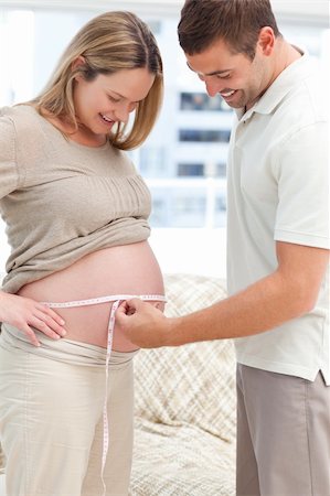 simsearch:400-04266844,k - Attentive man measuring his pregnant wife's waist standing in the living room Stock Photo - Budget Royalty-Free & Subscription, Code: 400-04266857