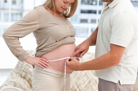 simsearch:400-07322828,k - Lovely couple measuring the waist of the pregnant wife standing in the living room Fotografie stock - Microstock e Abbonamento, Codice: 400-04266858