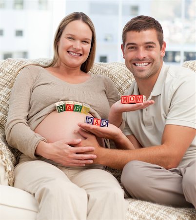 simsearch:400-08253730,k - Lovely future parents holding cubes forming the words mom ,dad and baby in the living-room Stock Photo - Budget Royalty-Free & Subscription, Code: 400-04266853